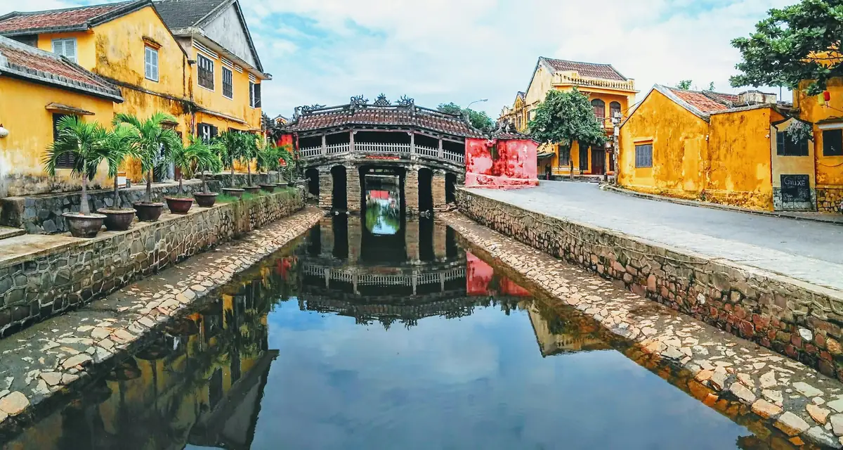 A covered wooden bridge reflected in still canal water