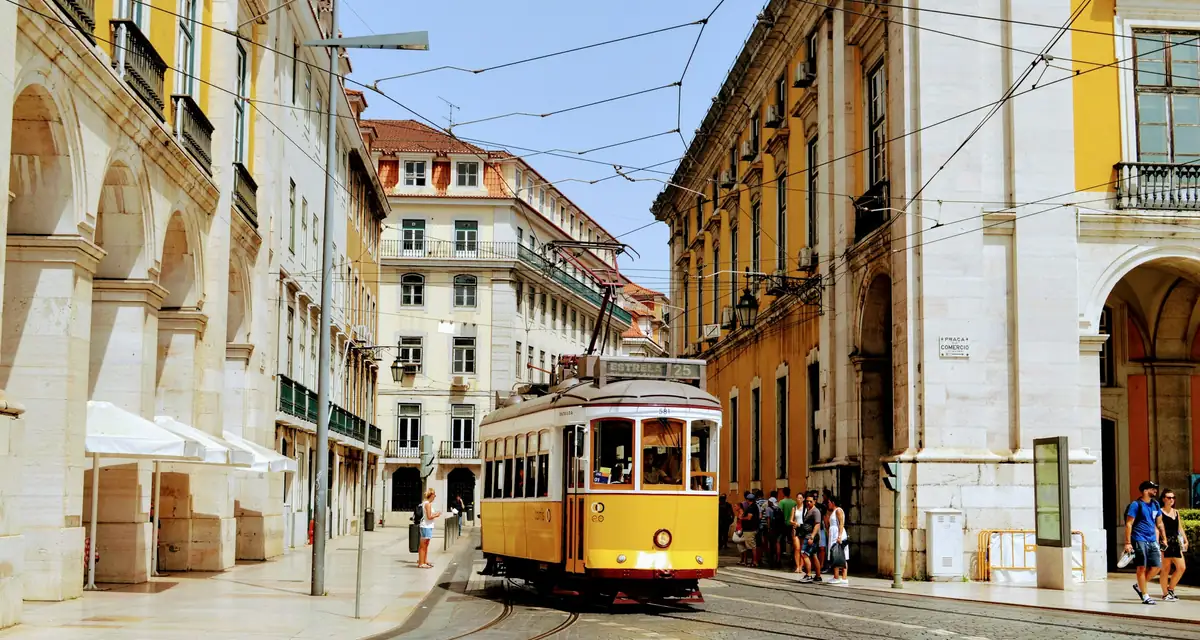A yellow tram climbing a street between pale stone buildings