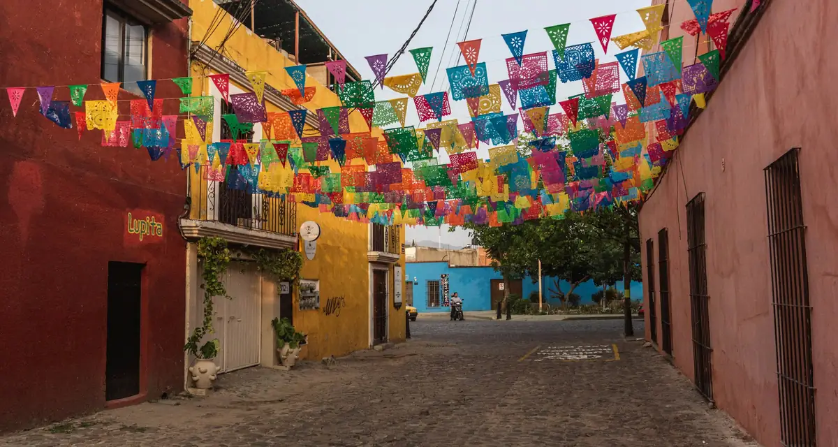 Papel picado bunting strung above a narrow street of ochre walls