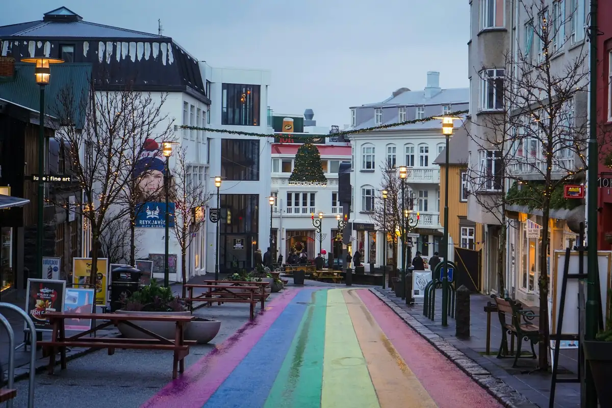 A rainbow-painted street between low painted buildings