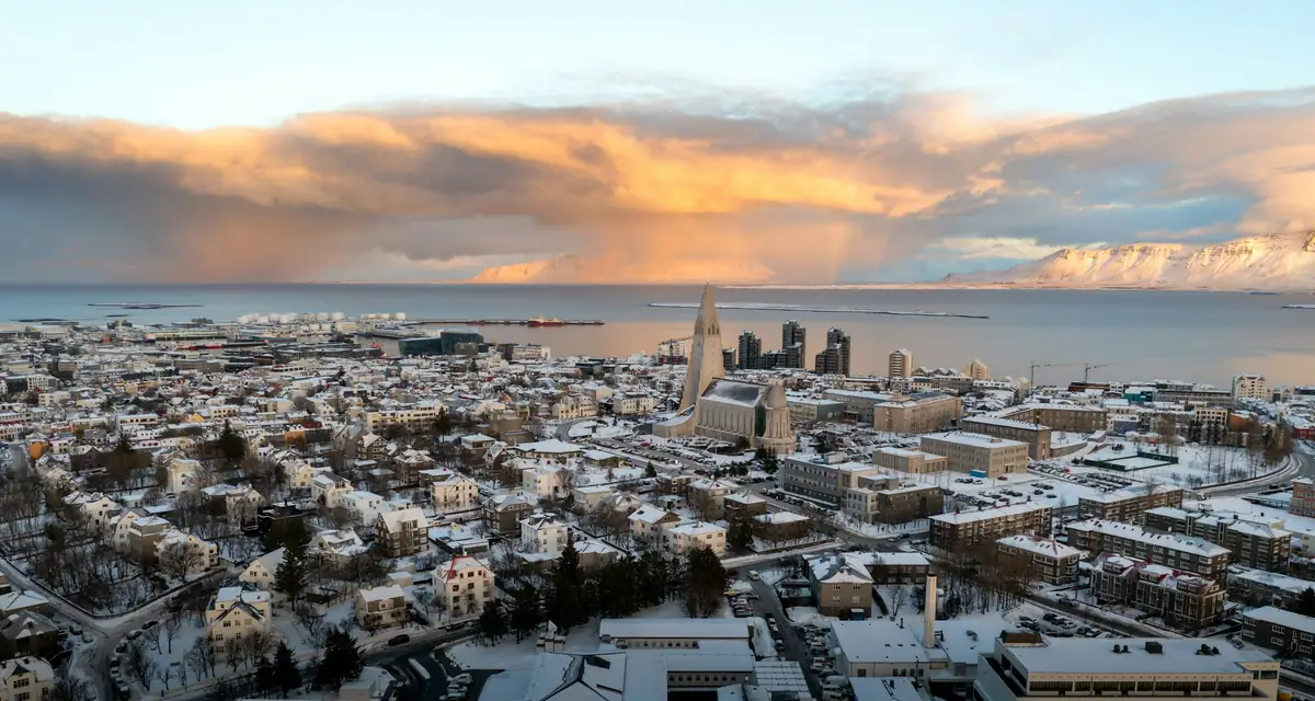 Snow-covered rooftops with the sea and mountains beyond
