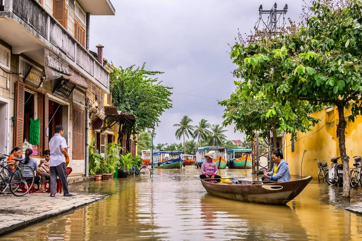 Small boats on a canal beside yellow shophouses