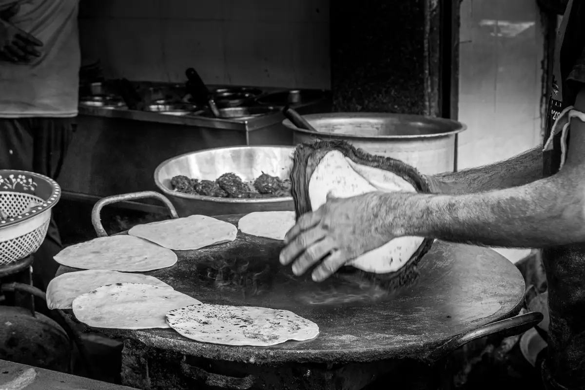 Hands turning flatbread on a large griddle