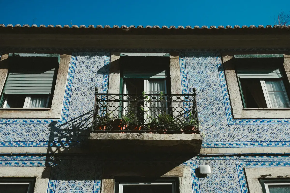 The blue-tiled façade and iron balconies of the building