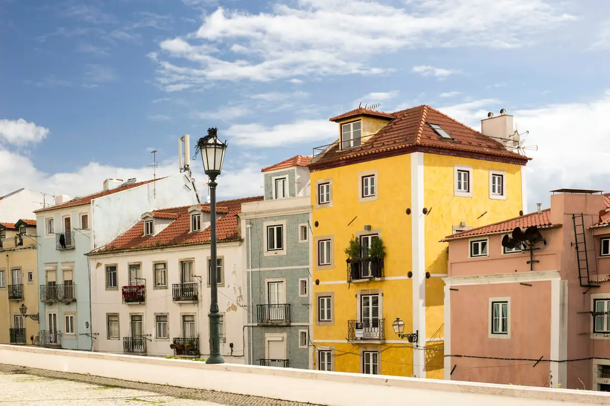 Pastel buildings stacked up the hillside under a cloudy sky
