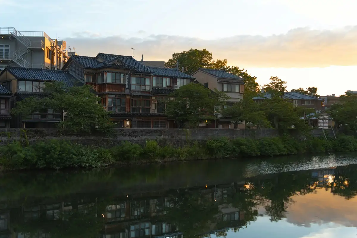 Wooden houses reflected in the river at sunset