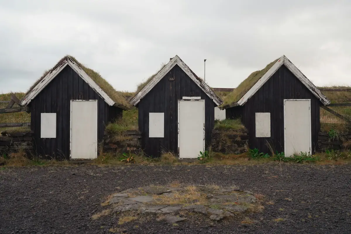Three black turf-roofed houses in a row