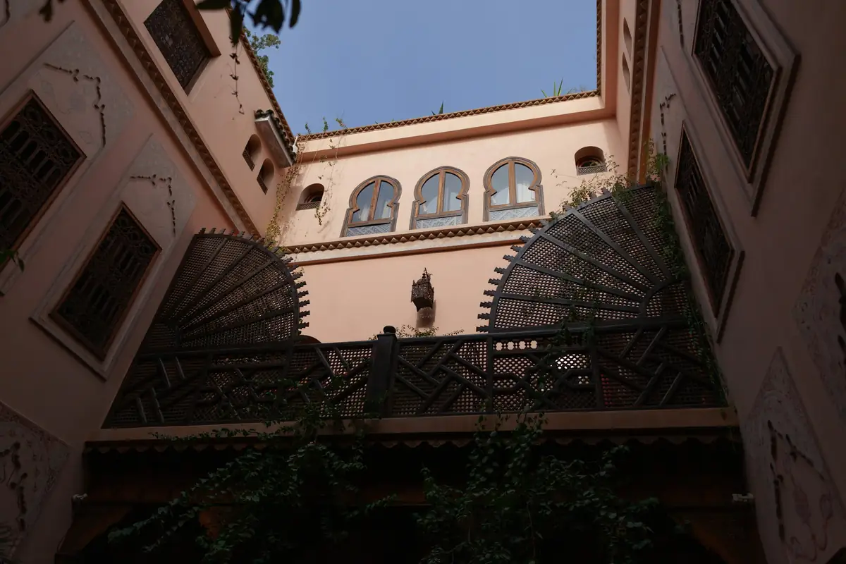 A riad courtyard seen from below, with arched windows and iron screens