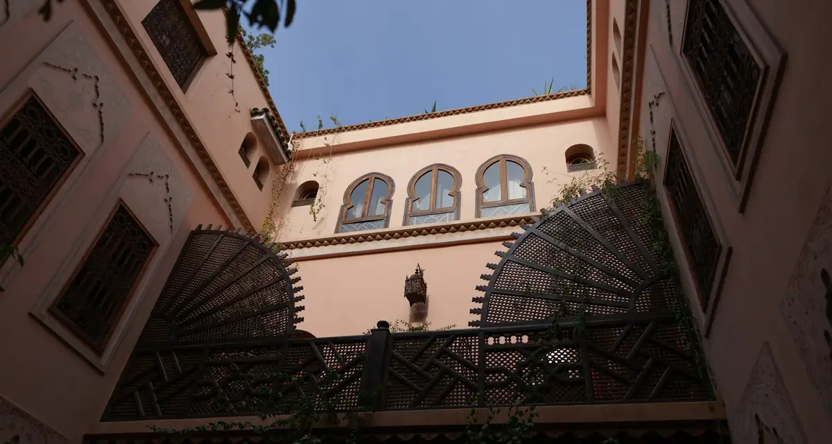 A riad courtyard seen from below, with arched windows and iron screens