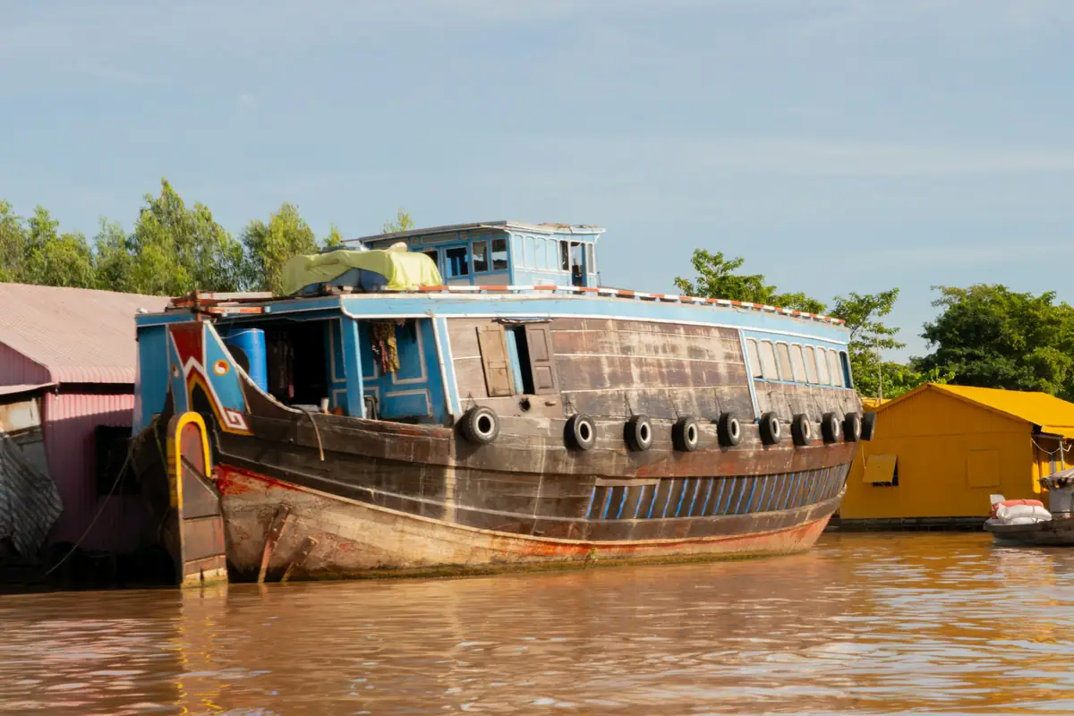 An old wooden river boat moored at a muddy bank