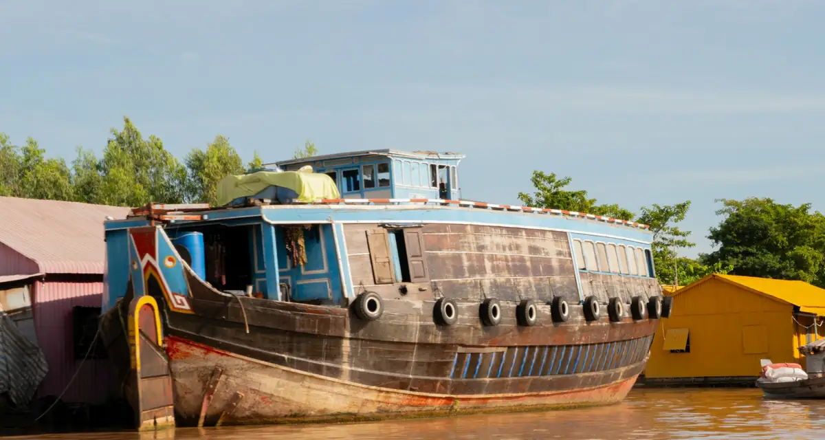 An old wooden river boat moored at a muddy bank